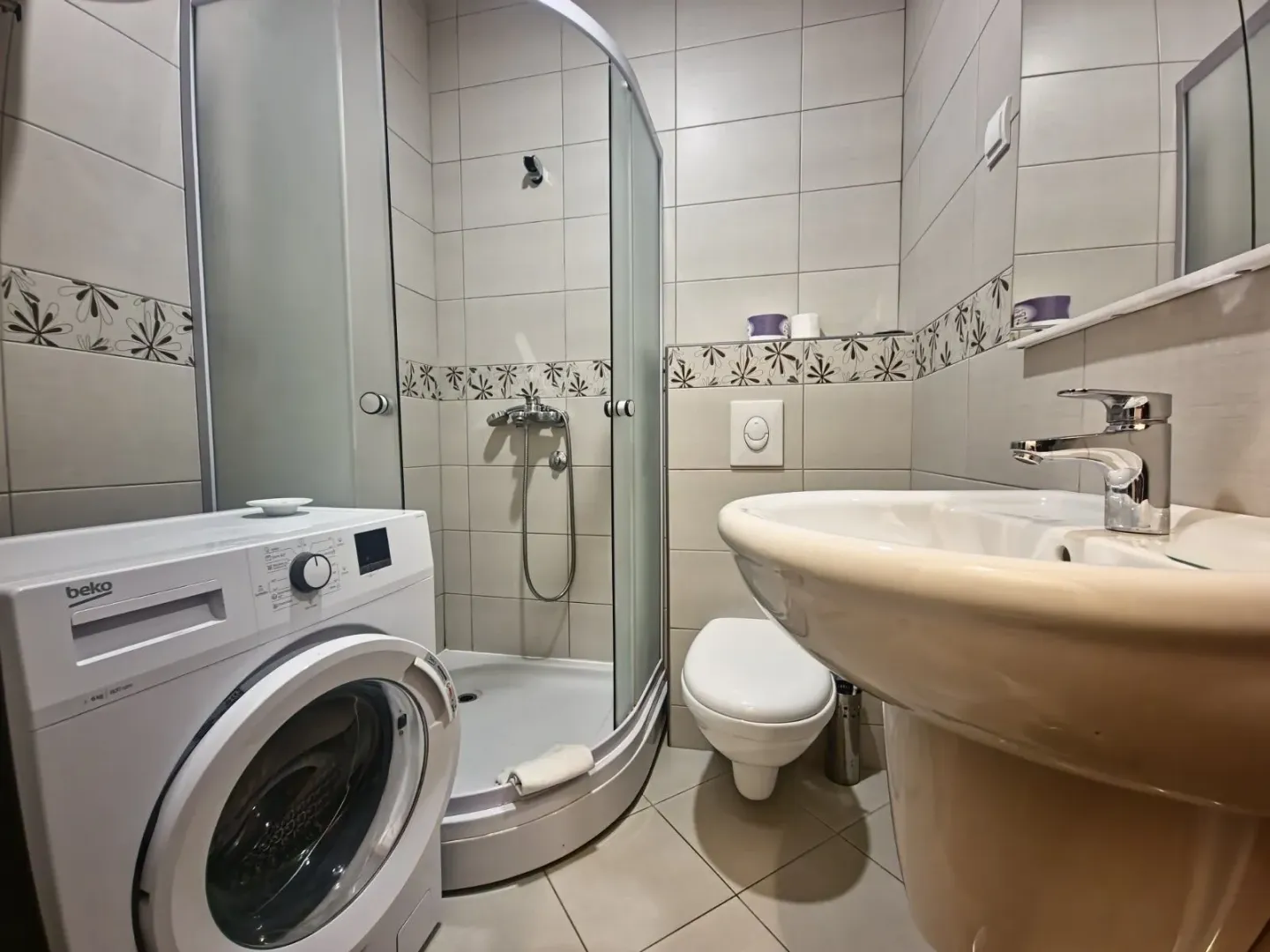 Bathroom equipped with a shower cabin, washbasin, toilet, and washing machine.