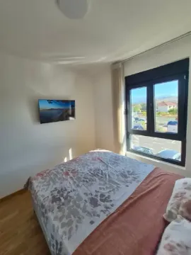 Spavaća soba sa bračnim krevetom, TV-om na zidu i prozorom sa pogledom na okolinu. - image 6
