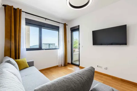 Dnevna soba sa garniturom, televizorom na zidu i izlazom na terasu. - image 23
