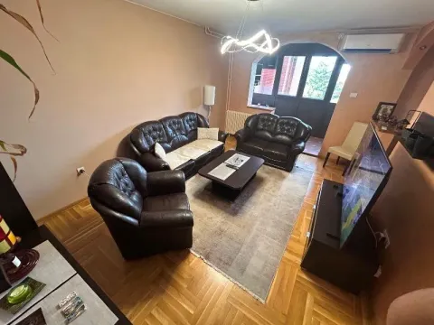 Dnevna soba sa garniturom od tamne kože, drvenim parketom i izlazom na terasu. - image 2