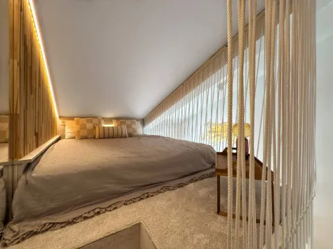 Attic bedroom with a double bed and decorative partition ropes. - image 8