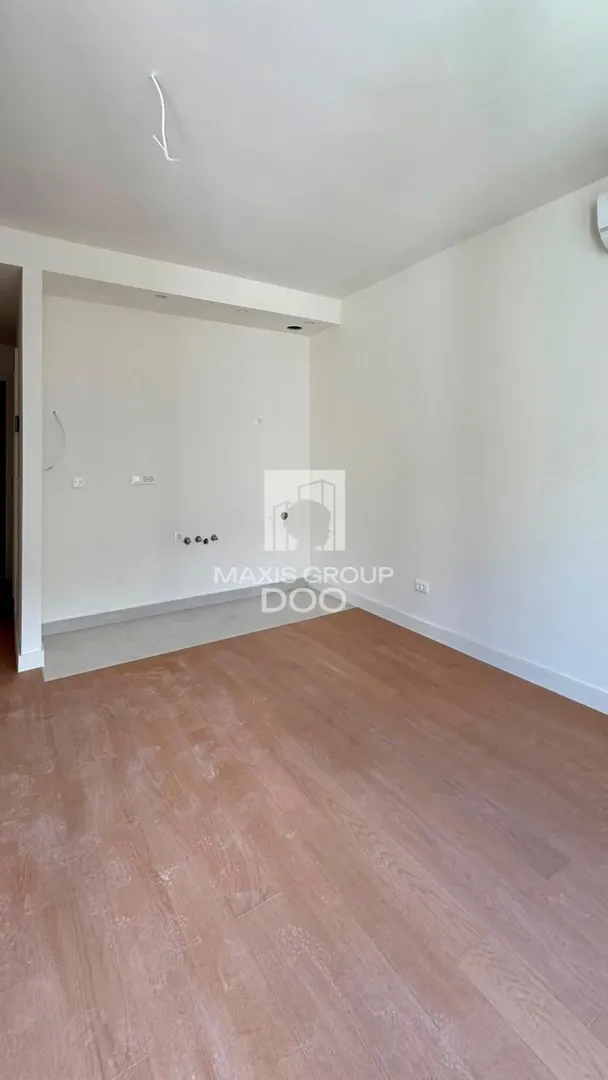 Empty room with wooden flooring and white walls.