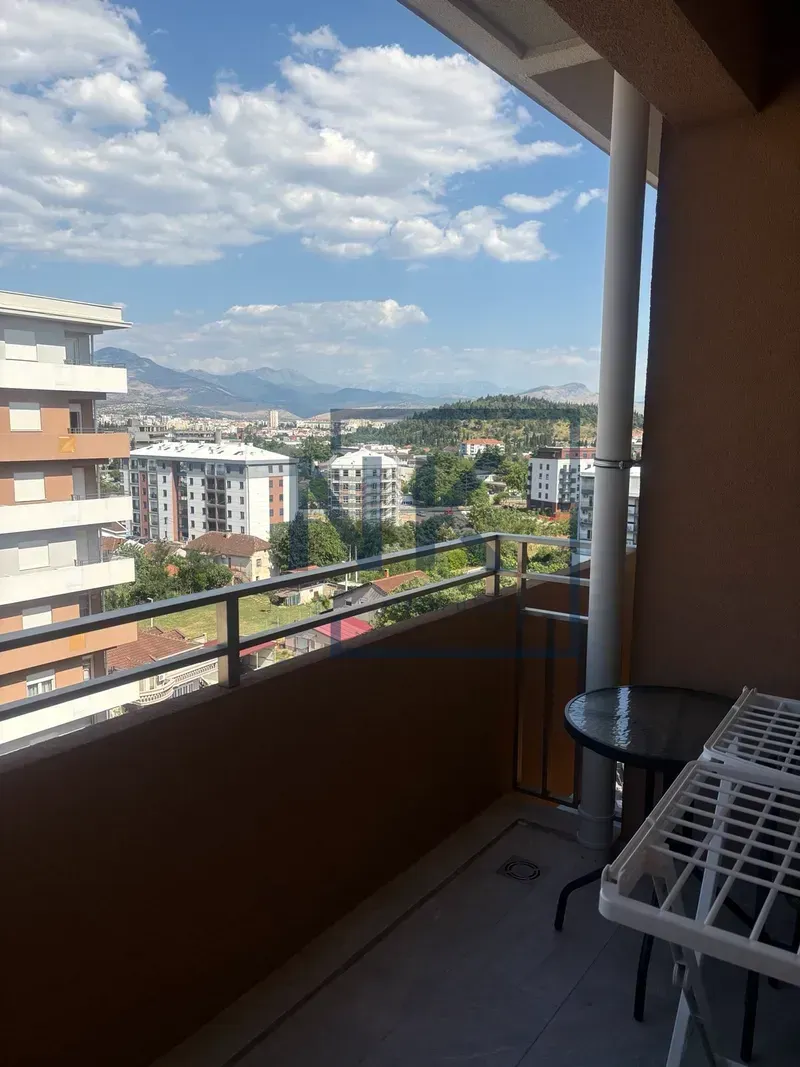 Natkriveni balkon sa pogledom na grad i okolne planine.