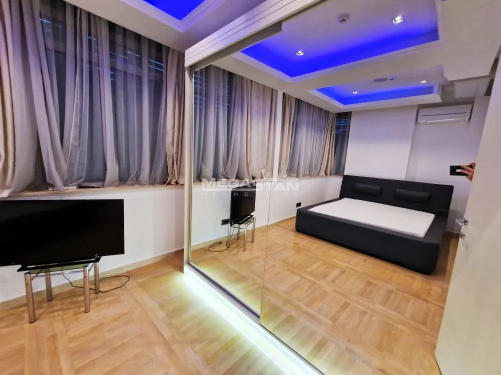 Bedroom with a double bed, large mirror, and drop ceiling with lighting.