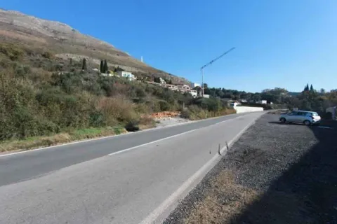 Pogled na asfaltirani put i okolni pejzaž sa brdom u pozadini. - image 4
