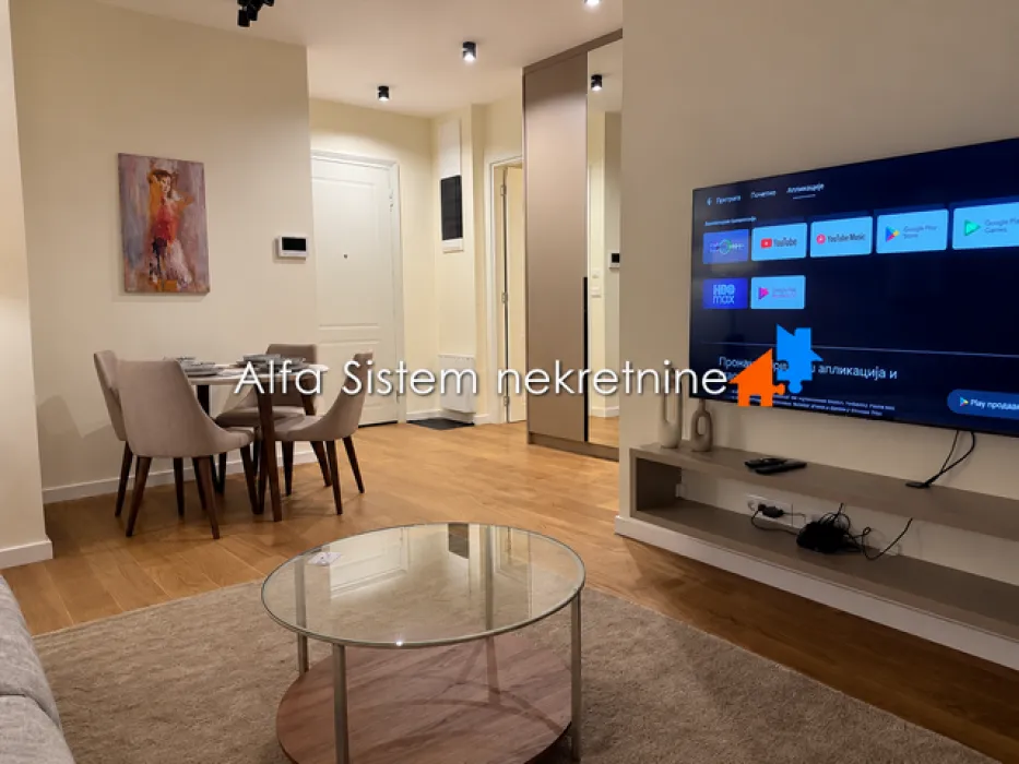Living room with a dining area, television, and wooden flooring.