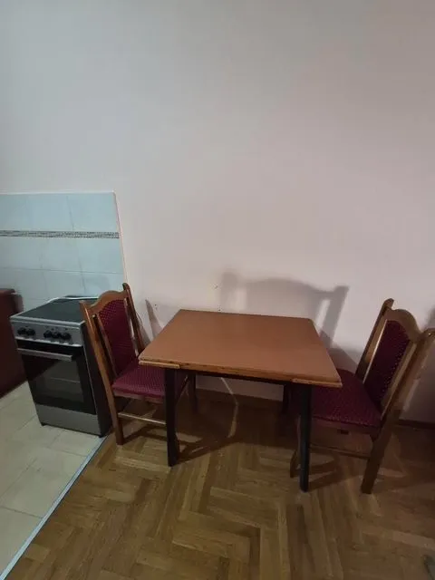 Dining table with chairs and a part of the kitchen with a stove.