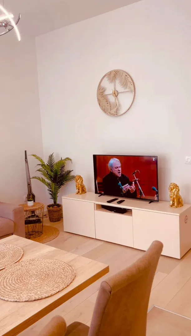 Svijetla dnevna soba sa TV komodom i ukrasnim detaljima.