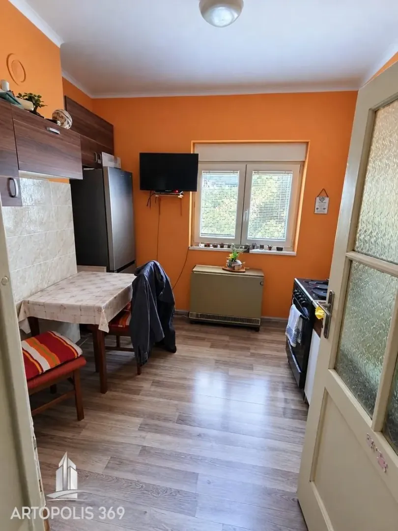 Kuhinja sa trpezarijskim stolom i narandžastim zidovima.