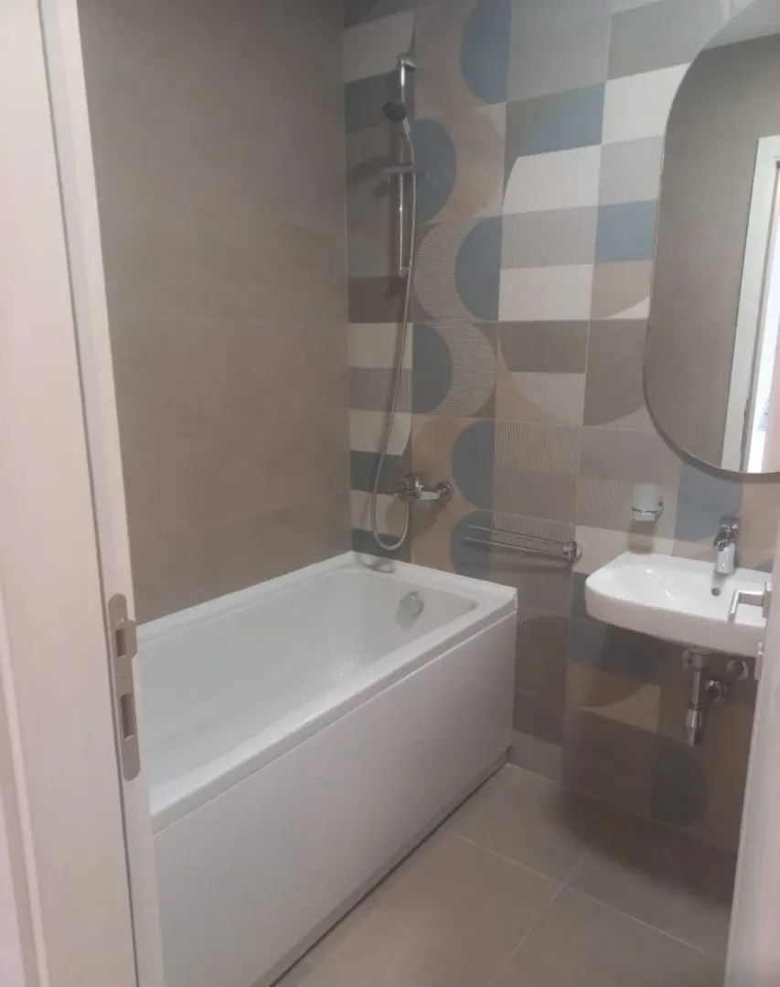 Bathroom with a bathtub, washbasin, and decorative wall tiles.