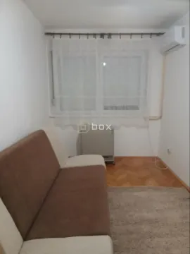 Manja dnevna soba sa braon-belom sofom i prozorom sa zavesama. - image 3