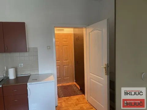 View from the kitchen towards the hallway with wooden flooring and an open door. - image 6