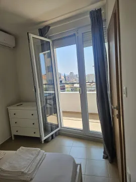 Bedroom with balcony access and city view. - image 9