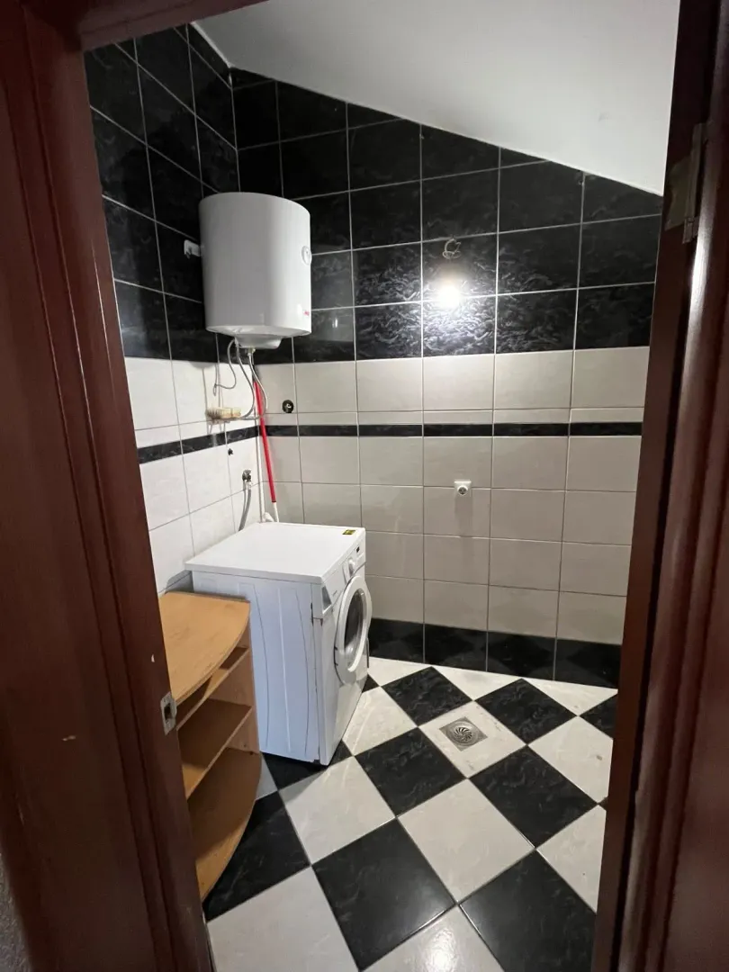 Manje kupatilo sa crno-bijelim pločicama, bojlerom i veš mašinom.