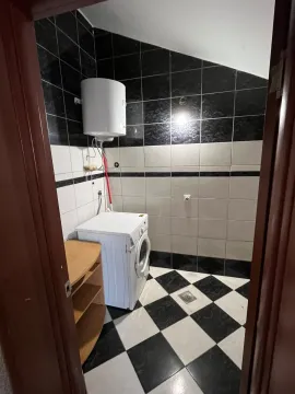 Manje kupatilo sa crno-bijelim pločicama, bojlerom i veš mašinom. - image 4
