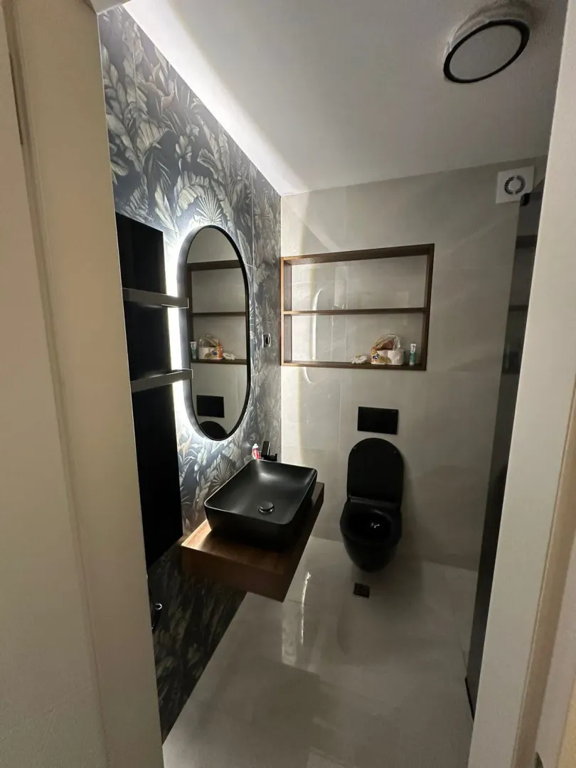 Moderne opremljeno kupatilo sa crnim umivaonikom i šoljom.