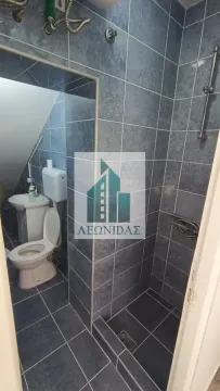 Kupatilo obloženo tamnim pločicama sa tuš kabinom i toaletom. - image 10