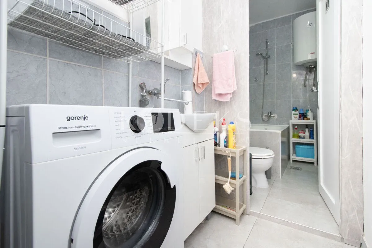 Bathroom with a washing machine, washbasin, and bathtub.