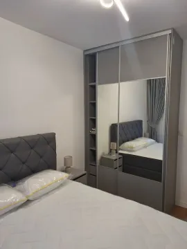Svijetla spavaća soba sa modernim sivim krevetom i velikim ugradnim plakarem sa ogledalima. - image 9