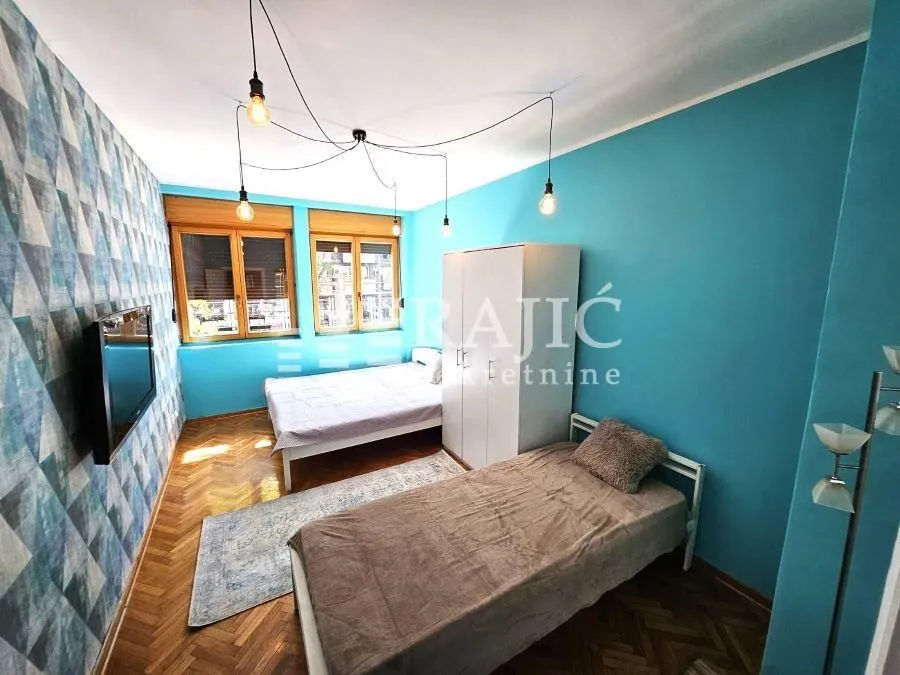 Furnished bedroom with two beds and blue walls.