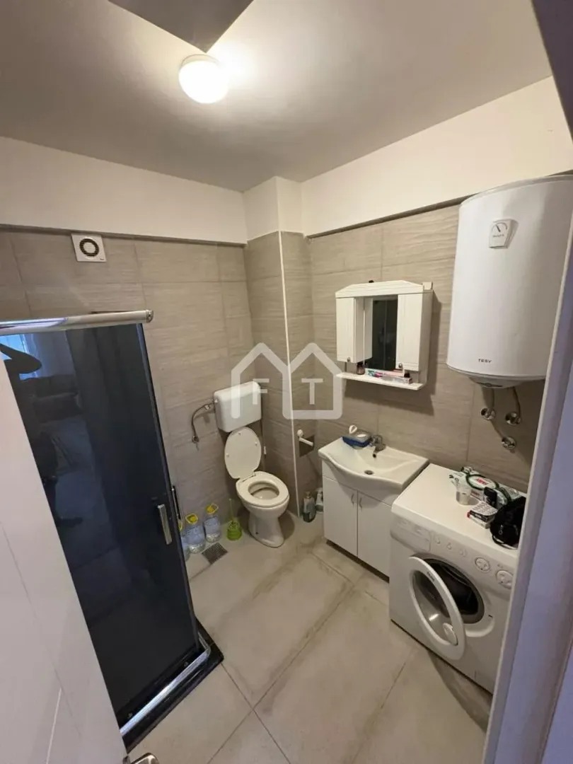 Bathroom equipped with a shower cabin, toilet, sink, water heater, and washing machine.