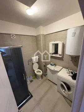 Bathroom equipped with a shower cabin, toilet, sink, water heater, and washing machine. - image 6