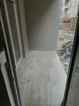Nenamješten balkon sa popločanim podom i pogledom na gradilište. - image 6