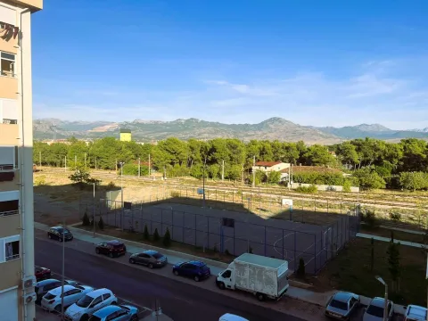 Pogled sa terase na sportski teren, parking i okolne planine. - image 11