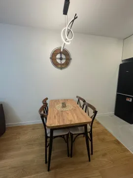 Dining area with a wooden table, chairs and a wall clock. - image 5