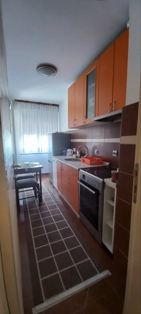 A narrow kitchen with orange cabinets.