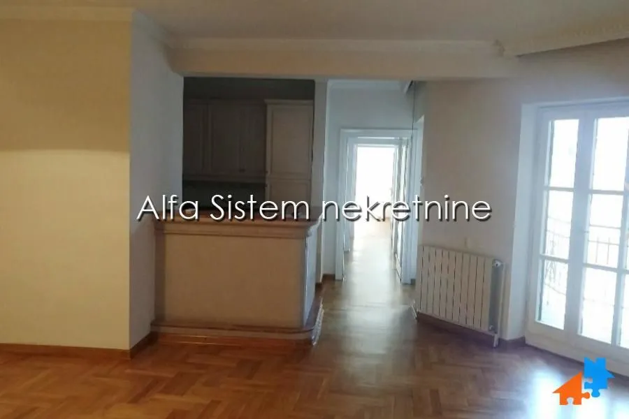 Spacious living room with parquet flooring and a view towards the hallway and kitchen.