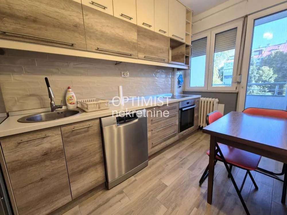 Kitchen equipped with wooden cabinetry and a dining table by the window.