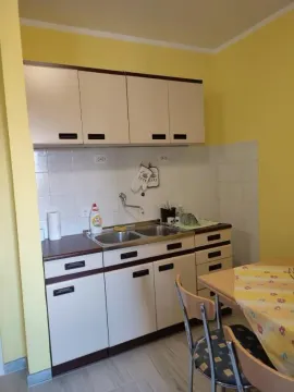 A simple kitchen with light cabinets and a dining table. - image 6