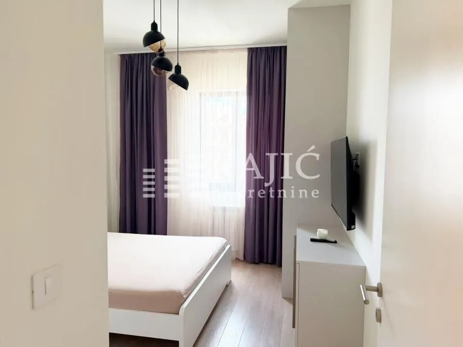 Furnished bedroom with a double bed and TV.
