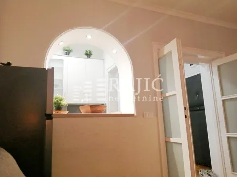 View from the room towards the kitchen with white elements through an arch. - image 5