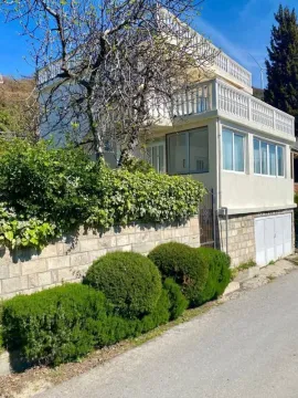 Exterior view of a multi-story house with a fenced yard and greenery. - image 11