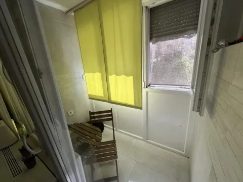 Zastakljeni balkonski prostor sa malim stolom, stolicama i roletnama na prozorima. - image 9