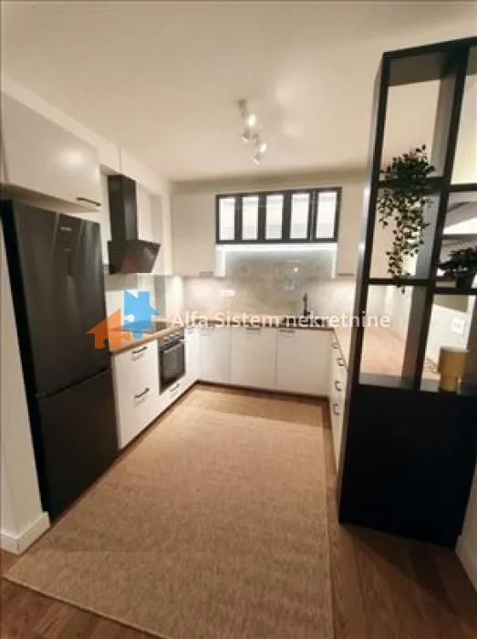 Modern U-shaped kitchen with built-in appliances and a black refrigerator.