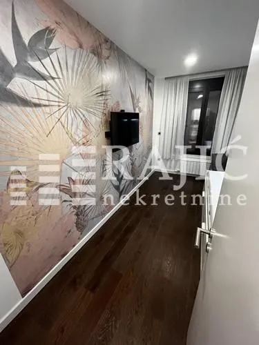 Smaller room with wallpaper on the wall and dark parquet flooring.