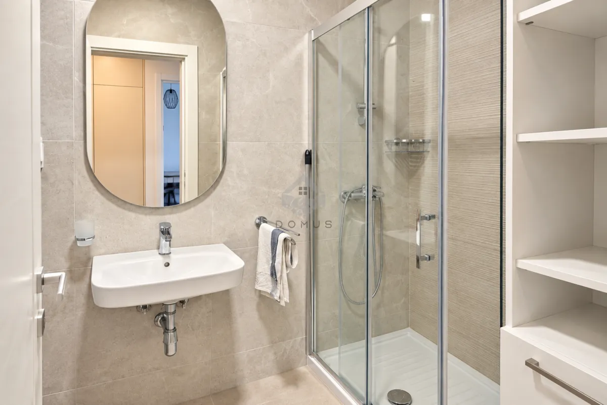 Modernly equipped bathroom with a washbasin, mirror, and shower cabin.