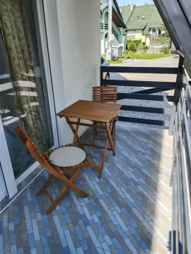 Manji namešteni balkon sa drvenim stolom i stolicama. - image 10