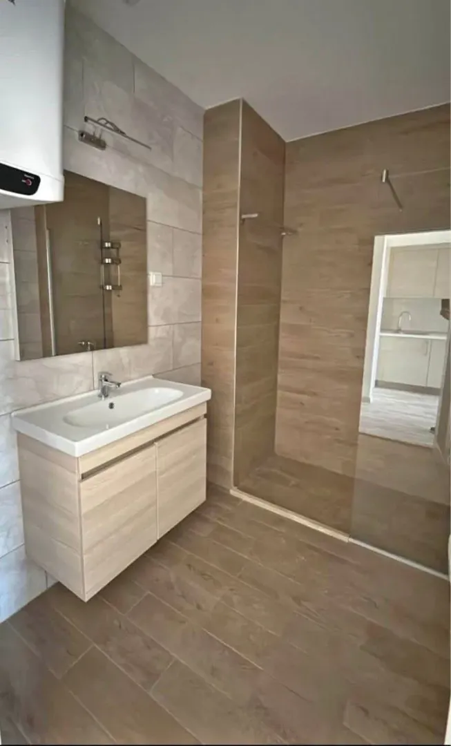 Savremeno opremljeno kupatilo sa tuš kabinom i umivaonikom.