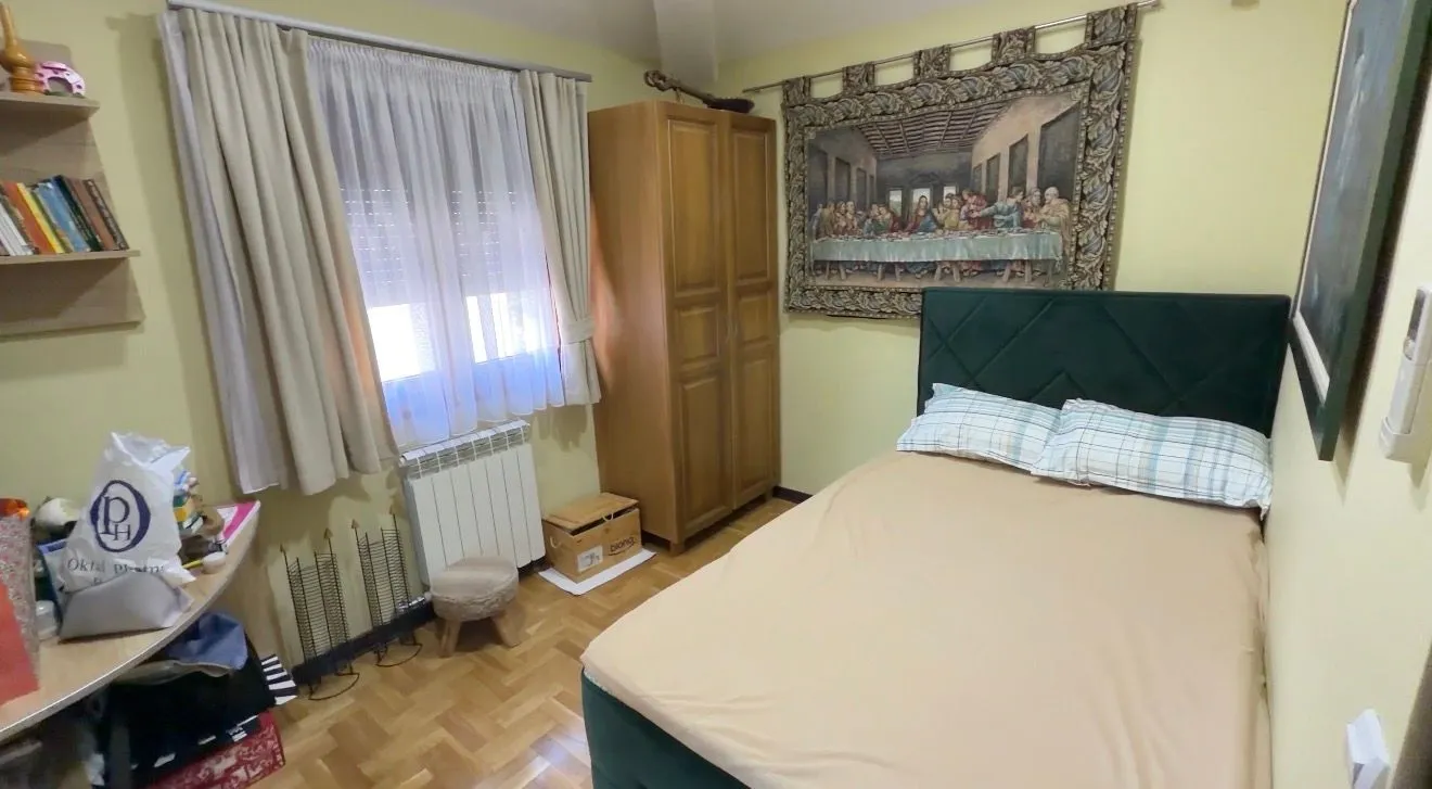 Namještena spavaća soba sa krevetom, ormarom i prozorom.