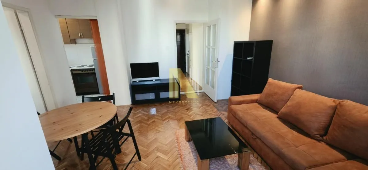 Dnevni boravak sa garniturom, trpezarijskim stolom i pogledom na kuhinju.