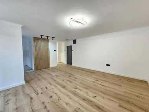 Prazna dnevna soba sa belim zidovima, drvenim podom i dekorativnim drvenim panelom. - image 16