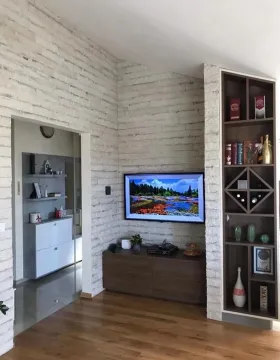 Living room with a decorative stone wall, television, and built-in shelving unit. - image 5