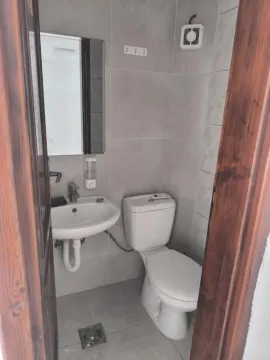 Smaller bathroom with a sink and toilet, tiled in gray and white. - image 4