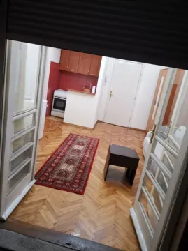 View through an open doorway into a living room with parquet flooring and a kitchen in the background. - image 3