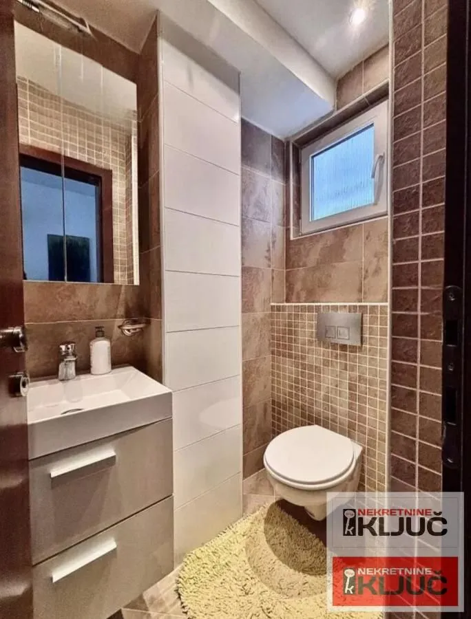 Manje kupatilo sa umivaonikom, WC šoljom i prozorom.