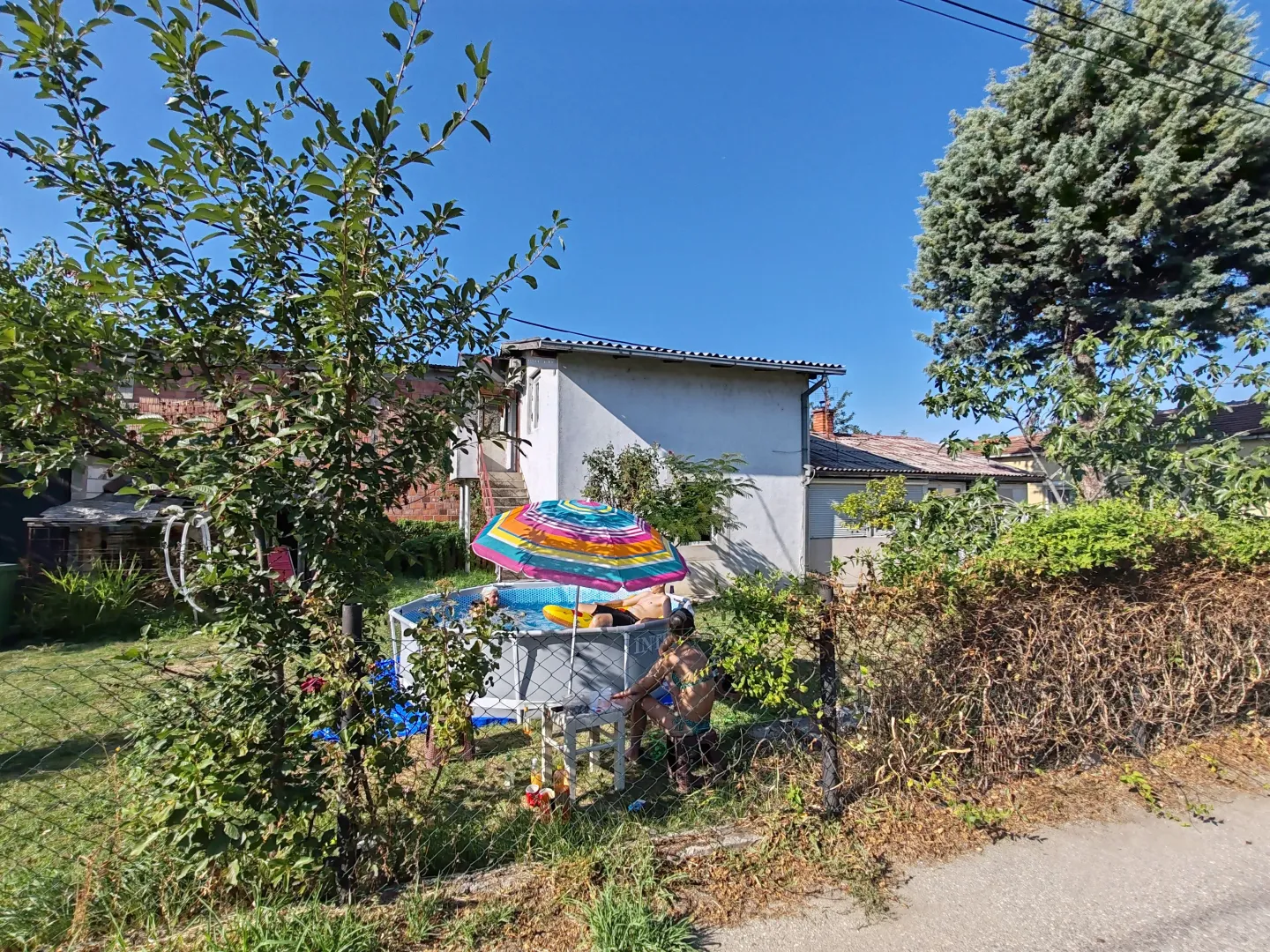 Dvorište kuće sa bazenom i suncobranom.